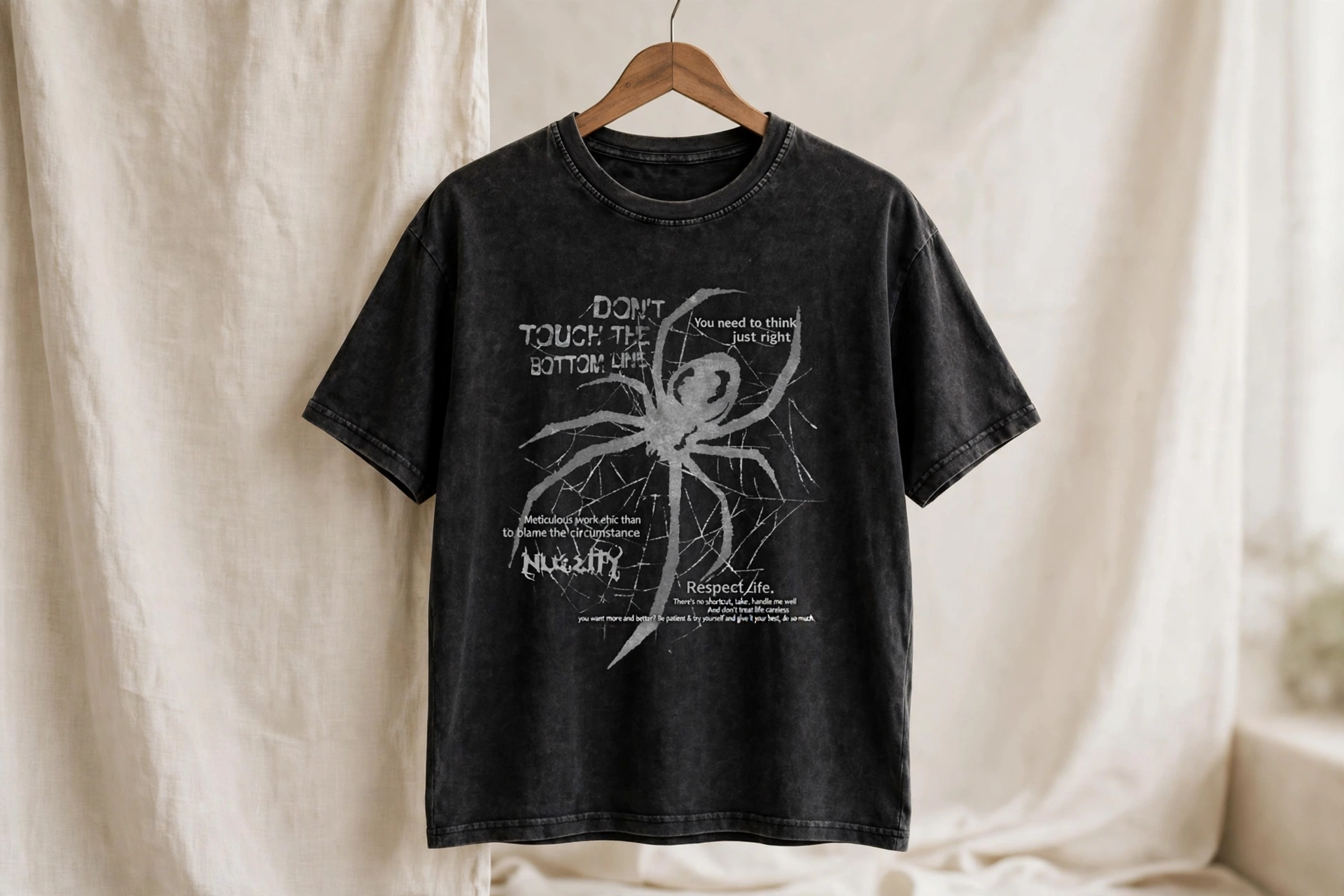 Black acid wash relaxed tailored fit t-shirt with white spider graphic and DON'T TOUCH THE BOTTOM LINE text hanging on wooden hanger in tailored polo studio with breathable sharp appearance patterns - hospitality staff golf clubs and corporate polo programs