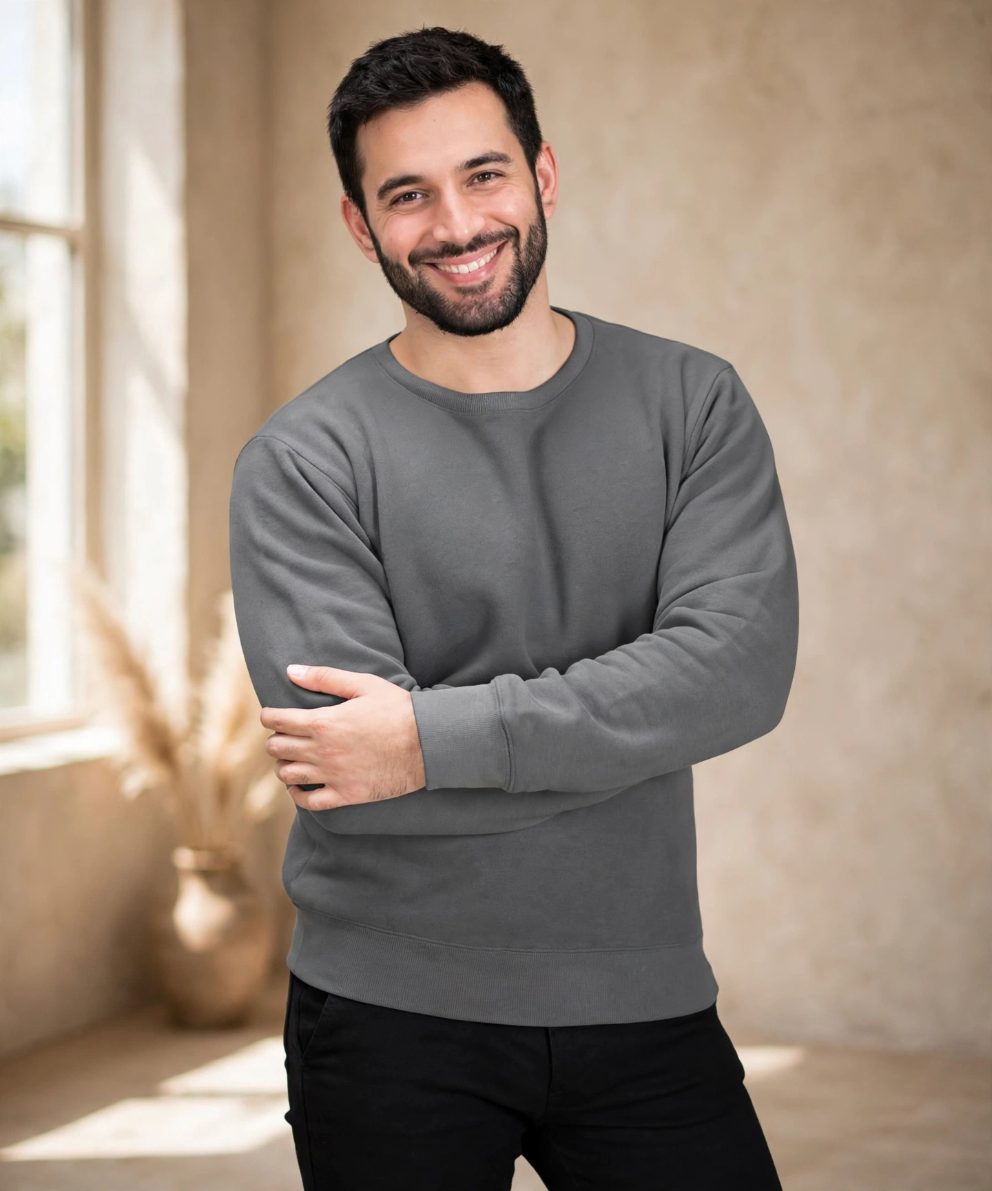 Recreated your grey crewneck in the exact same warm beige plaster studio style as the previous San Diego shot — 1144 by 1375, soft natural window light, premium editorial mood, product preserved exactly.